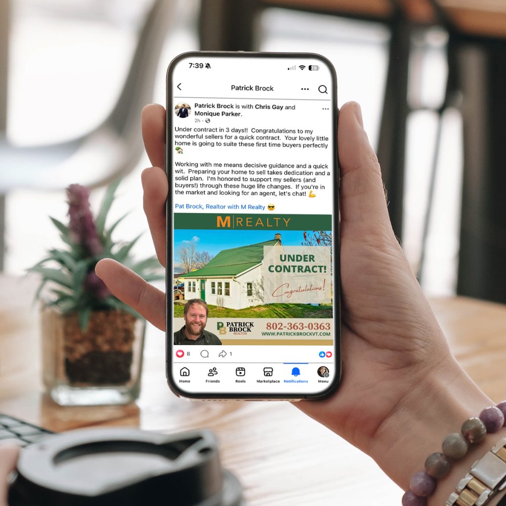 Hand holding a smartphone displaying a Facebook post from Patrick Brock, a realtor with M Realty, announcing an "Under Contract" listing.
