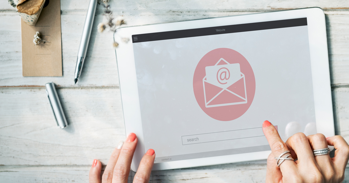 Hands hovering over an email icon on a tablet