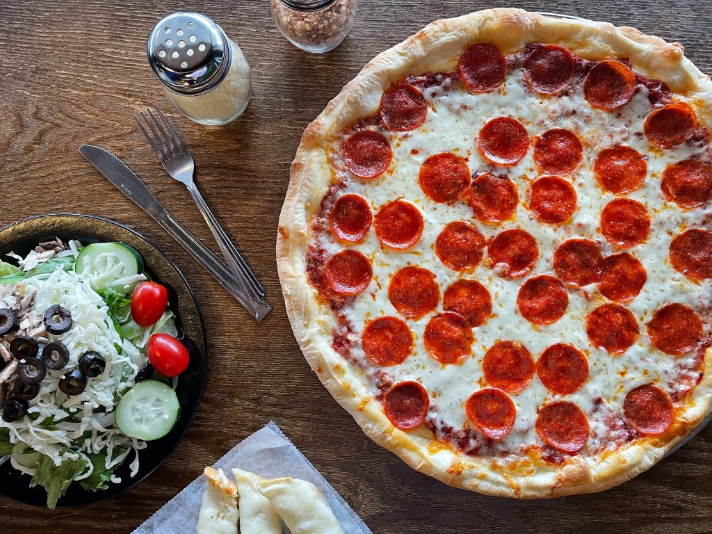 Overhead view of a pepperoni pizza and chef's salad