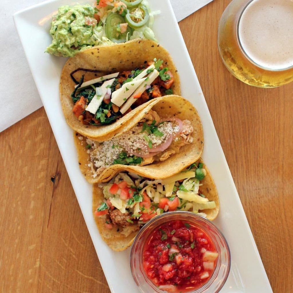 Overhead view of three tacos with salsa