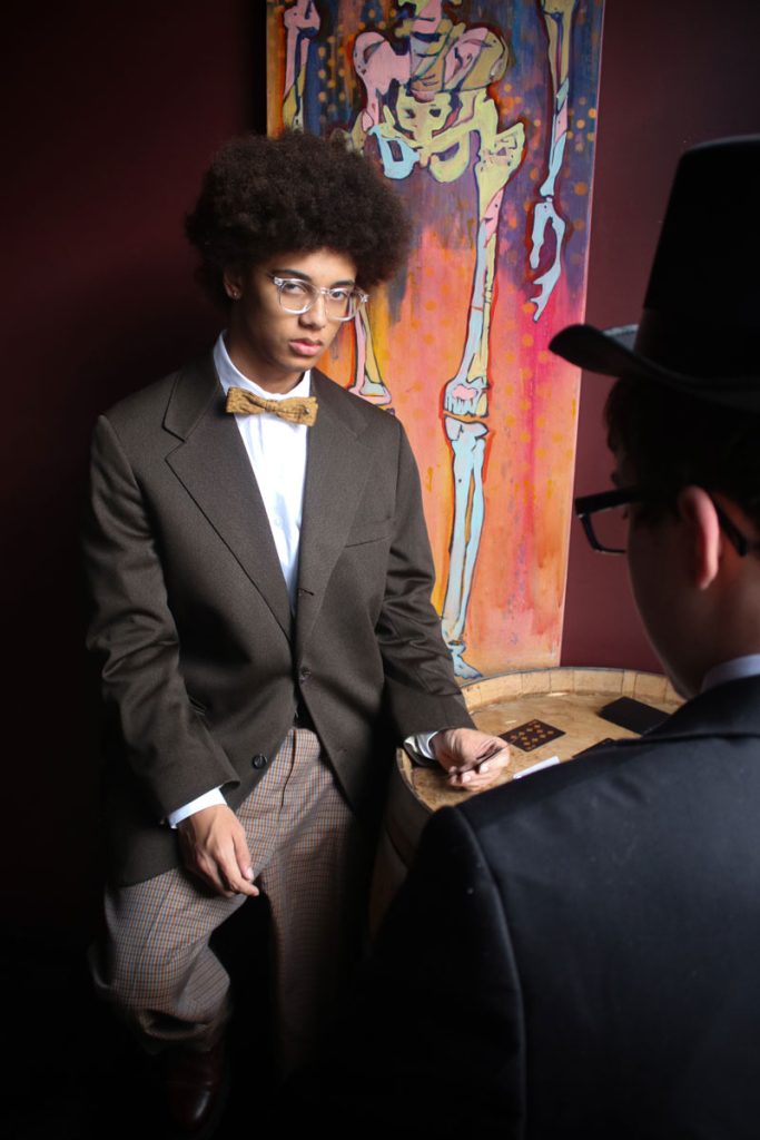 Teen in a suit with bow tie playing cards